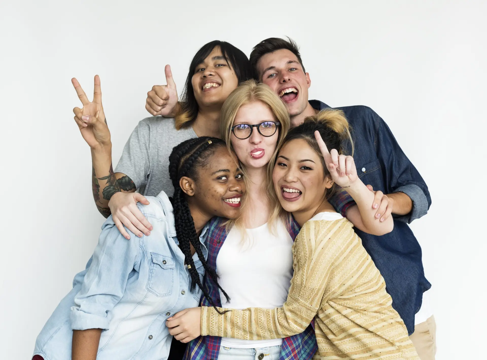 Groupe de cinq jeunes souriants, serrés les uns contre les autres, faisant des signes de la main sur fond blanc.